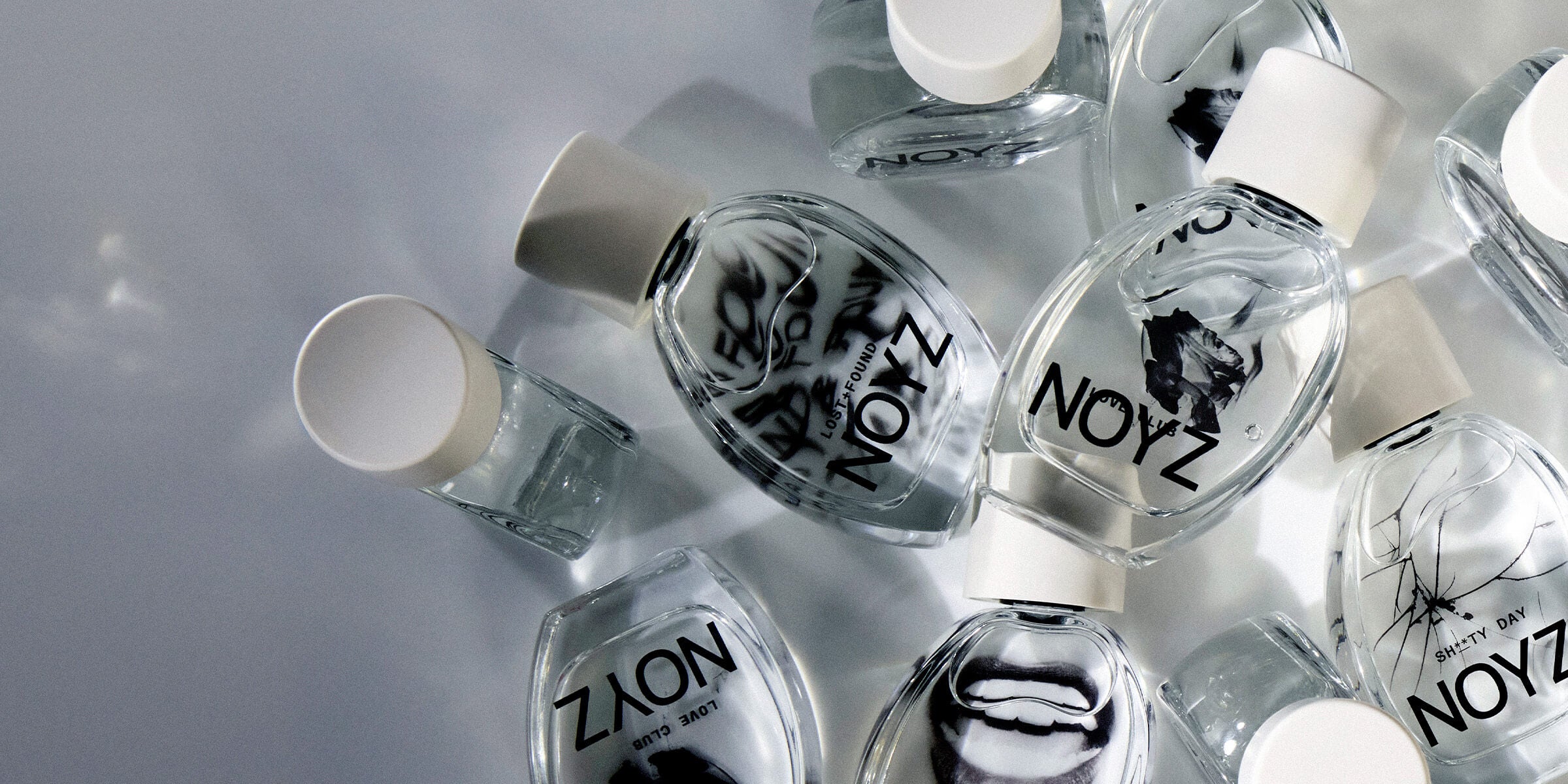 A collection of asymmetrical NOYZ perfume bottles reflecting off of each other