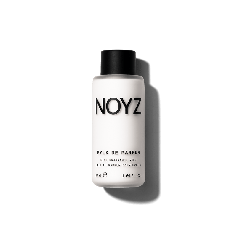A white bottle of NOYZ Mylk De Parfum with a black cap, centered against a solid black background.