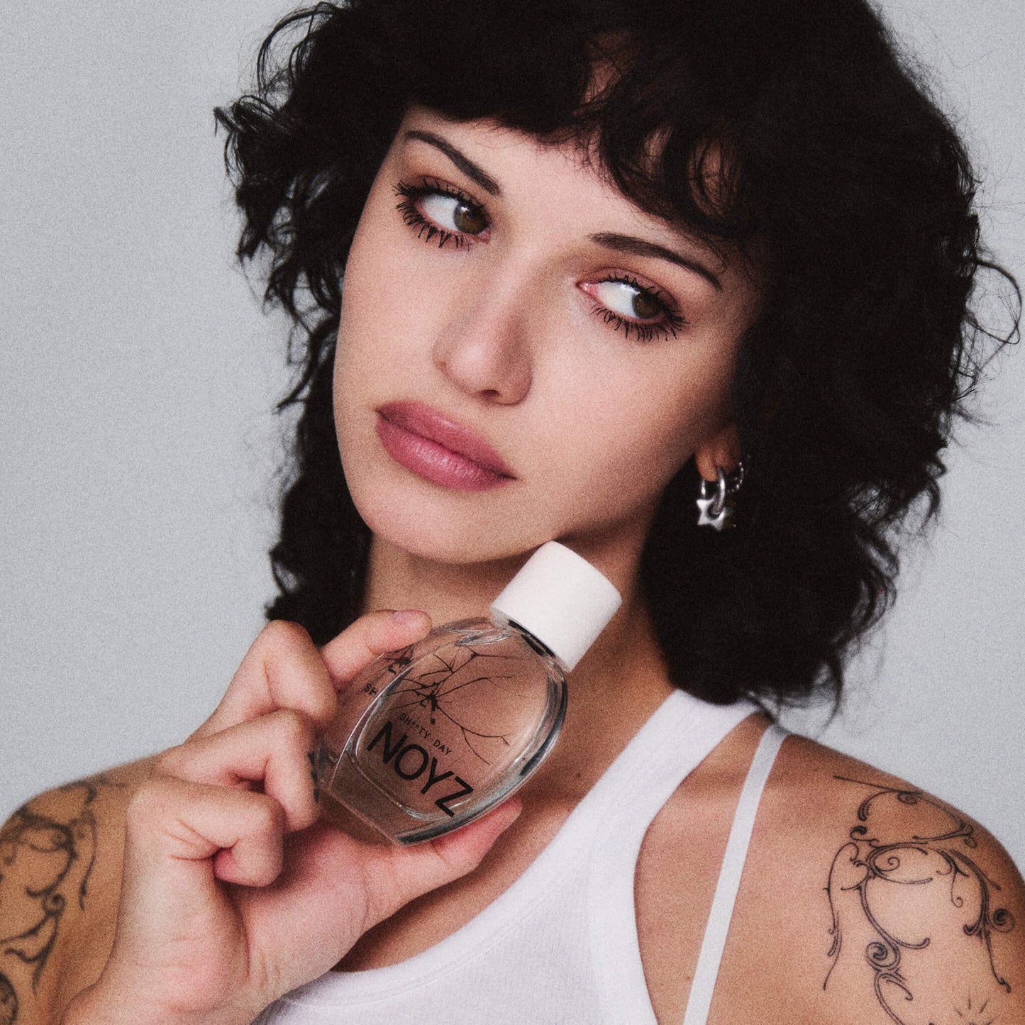 Intimate photo of a female model holding a bottle of Sh**ty Day Noyz unisex fragrance